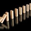 Wooden dominos with reflections representing a chain reaction isolated on black.