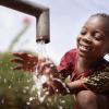 African girl drinking clean fresh water from a water tap outdoors 