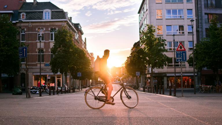 Person on a bike with sunset between two buildings in the background