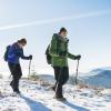 Senior couple with nordic walking poles hiking in snow-covered winter nature.