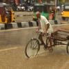 A man pedals a cycle rickshaw used for transporting goods during a flash flood