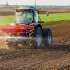Tractor spreading fertilizer on field before planting