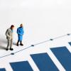miniature old people standing by a blue graph