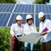 Three engineers studying plans in front of solar panels