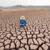 Person sitting on cracked earth by drought