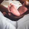 Baby`s foot of African black skin baby newborn, Placed on the father`s hand