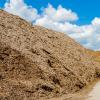Pile of wood chips at biomass co-generation plant at the foreground in focus with beautiful blue sky in the background out of focus 