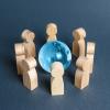Wooden figures around a blue glass globe. Concept of cooperation and collaboration