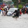 People, motorcycles and cars crossing a flooded road in Jakarta 