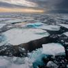 Wide angle view of Northern Arctic sea ice floes seen breaking up and melting leading into an atmospheric moody horizon with sunset