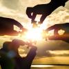 Collaborate four hands trying to connect a puzzle piece with a sunset background.