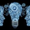 Communicating ideas. Cogs in the shape of two faces on either side of a lightbulb