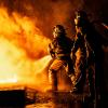 Two firefighters fighting fire with a hose and water