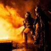 Two firefighters fighting fire with a hose and water