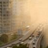 Air pollution scenic with cars on highway and yellow smoke in city.