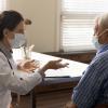 Female doctore with elderly male patient, both are wearing a mask.