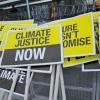 Yellow and black climate justice plackards leaning against a wall after a protest