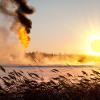 Vapour rising on a wetland with gas flaring in background