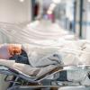 Newborn baby in first of many small, empty hospital beds.