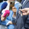 People holding microphones at a press conference, news conference or media event