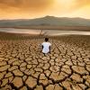Boy sitting on a cracked dry plain looking at a drying lake