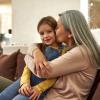 Older mother hugging her little girl on couch in livingroom