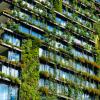 Green skyscraper building with plants on the facade.