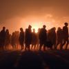 Group of refugees outlined against the setting sun.