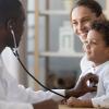 Pediatrician holding stethoscope examines patient during a doctor's visit with mother