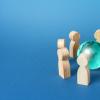 Wooden people figures surround a blue earth globe representing cooperation and collaboration