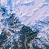 Greenland ice sheet and its edges, melt ponds, snowy mountain peaks cast long shadows in the evening sunlight. Elements of this image furnished by NASA.