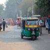 Colorful Tuk-Tuk vehicle and pedestrians in crowded traffic of Delhi with visible smog of air pollution 