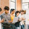 Multiethnic diverse group of happy young adult using information technology devices together