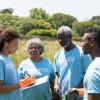 young women writing on a clipboard and instructing volunteers in a field