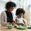 mother with daughter making salad together, chopping fresh vegetables on board