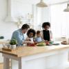 Happy multinational family with kids preparing salad in kitchen