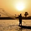 Fisherman throwing his net during sunset 