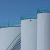 Large industrial storage tanks with green railings against a clear blue sky.